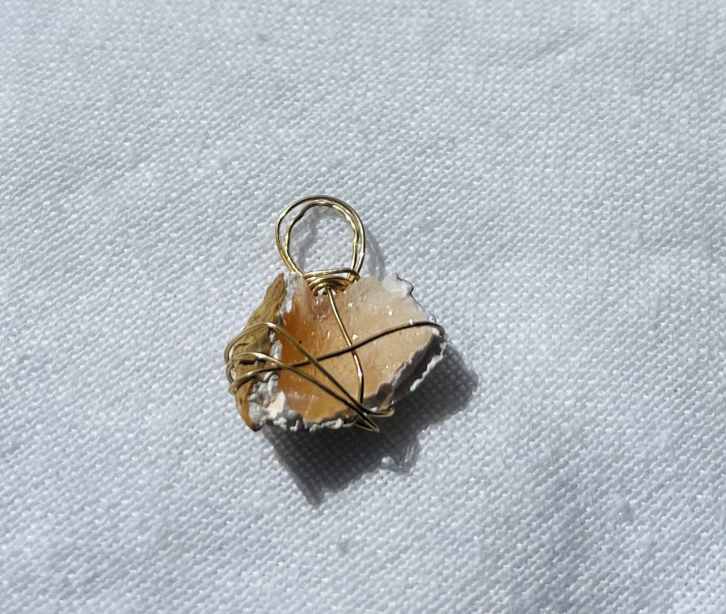 Peachy pink pendant with sparkling highlights wrapped in tarnish-resistant wire