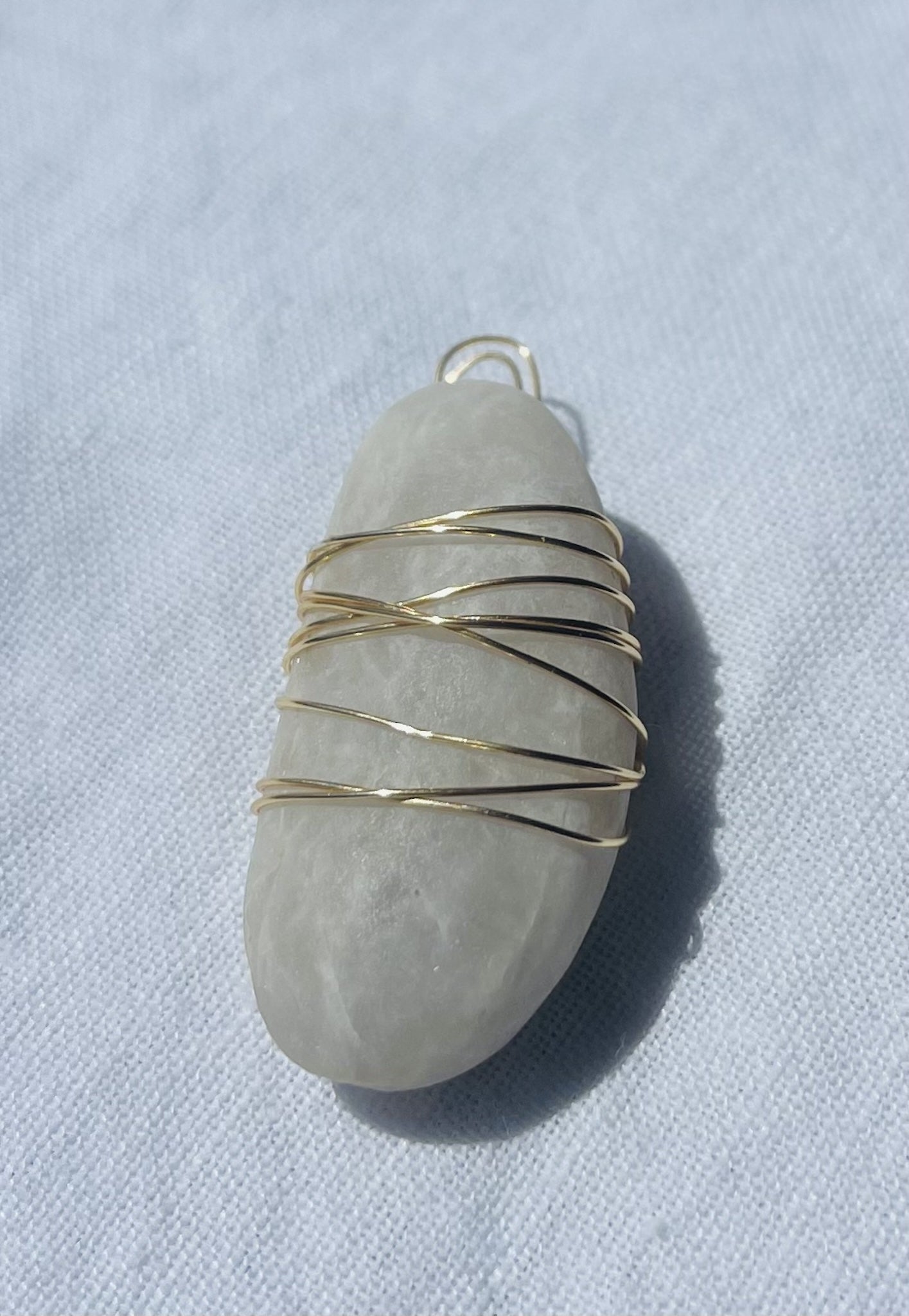 Light grey pendant with unique markings and gold-coloured tarnish-resistant wire