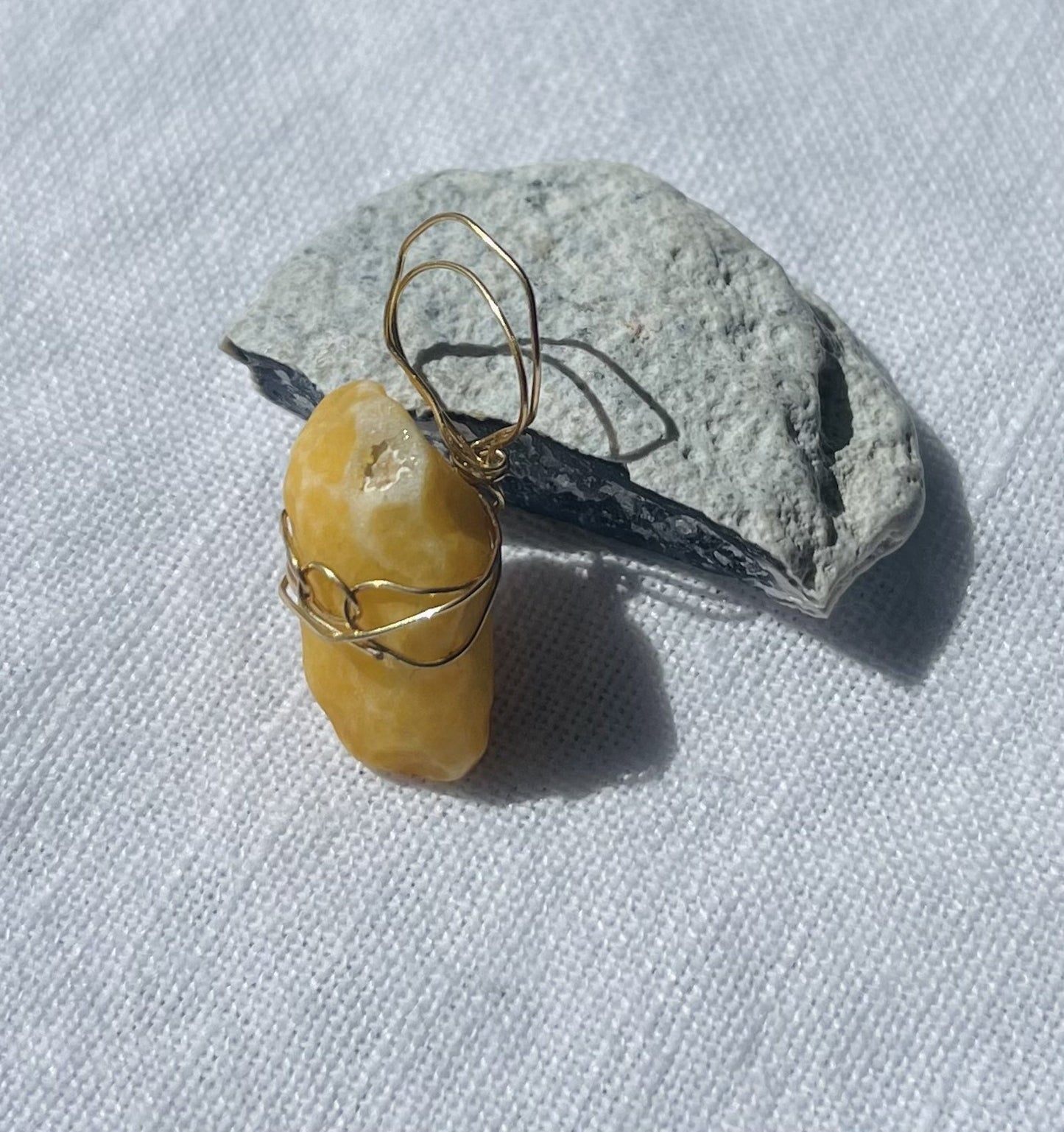 Mustard-golden pendant with circular wire design and sparkling highlights