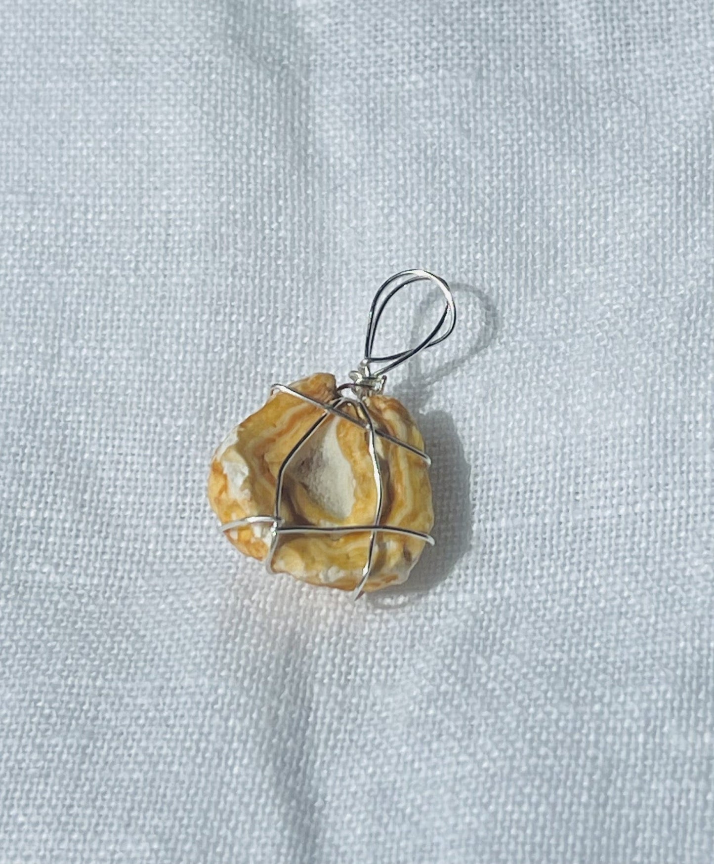 A golden Wise Rock pendant with a sparkly geode center, wrapped in silver-coloured wire, radiating warmth and sophistication