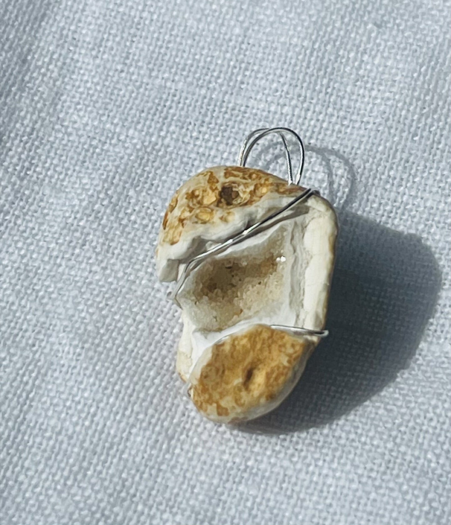 A golden geode pendant wrapped in silver-coloured wire, blending subtle sparkle with warm golden hues