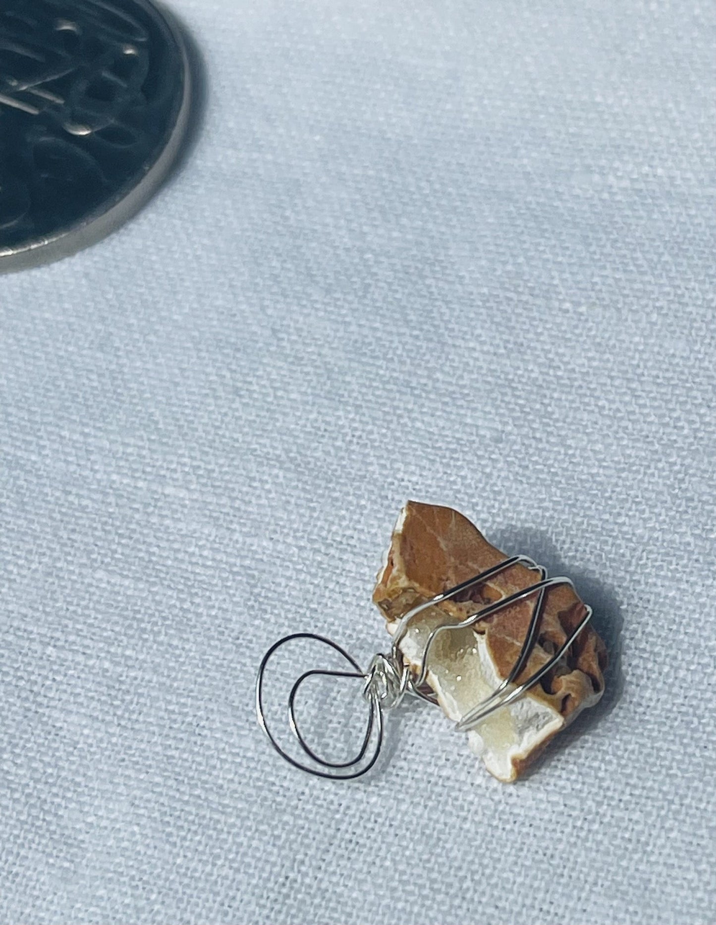 Sparkly geode pendant featuring a white geode cave in earthy tones, wrapped in silver-coloured wire