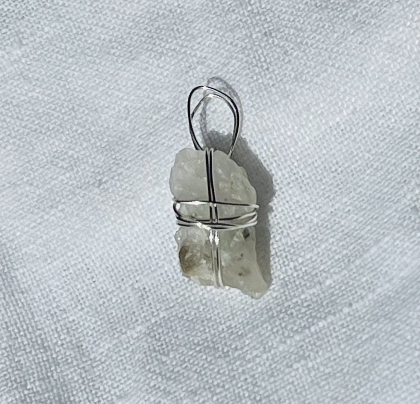 Translucent silver shimmer pendant wrapped in silver-coloured wire, photographed with a 20-cent coin for size reference