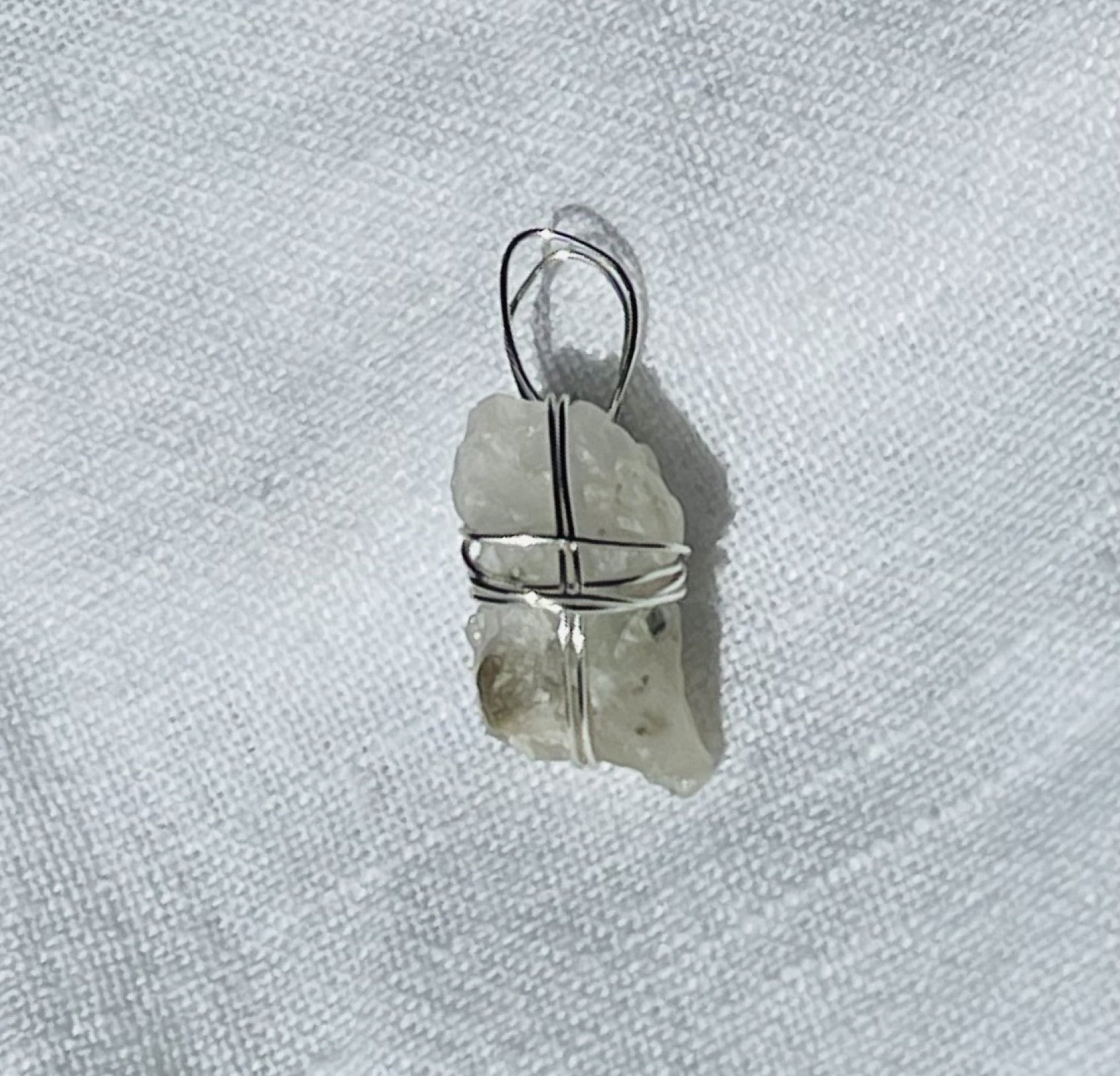 Translucent silver shimmer pendant wrapped in silver-coloured wire, photographed with a 20-cent coin for size reference